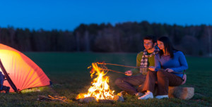 Camping night couple cook by campfire romantic